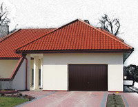 Brązowa brama garażowa uchylna w nowoczesnym domu z czerwoną dachówką, widok z lekkiego ukosa, kostka brukowa w odcieniach czerwieni i beżu.